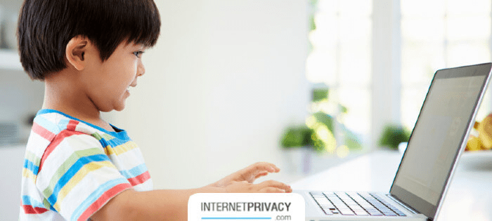 a little boy that is sitting in front of a laptop.