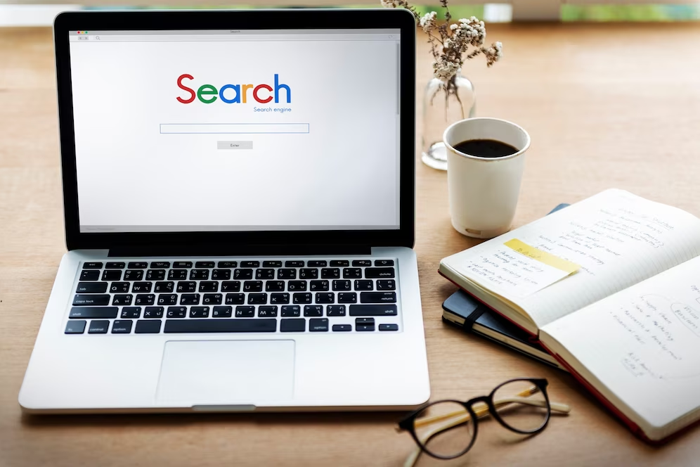 a laptop with search on it sitting on a wooden table.