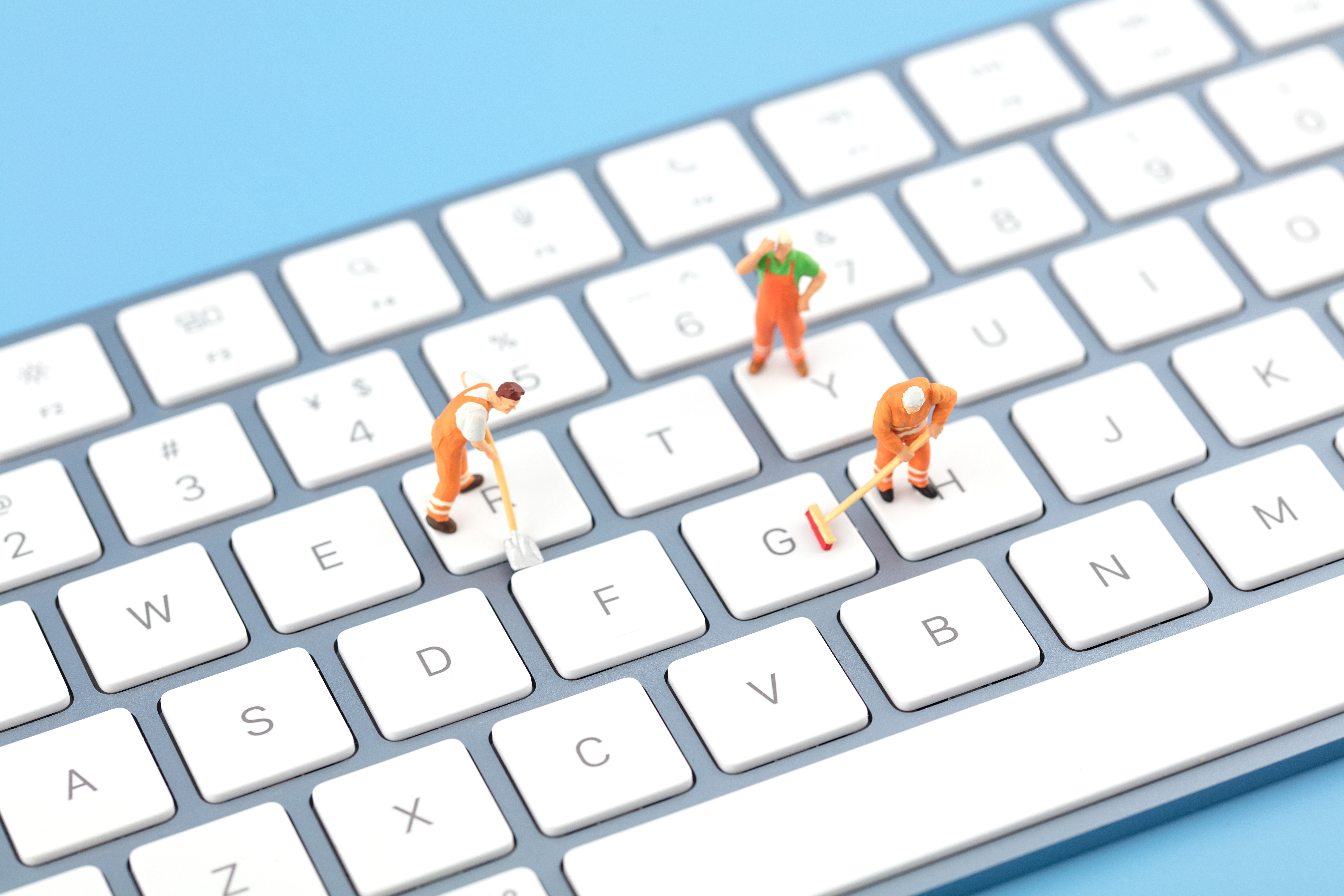 Miniature figures standing on a keyboard.
