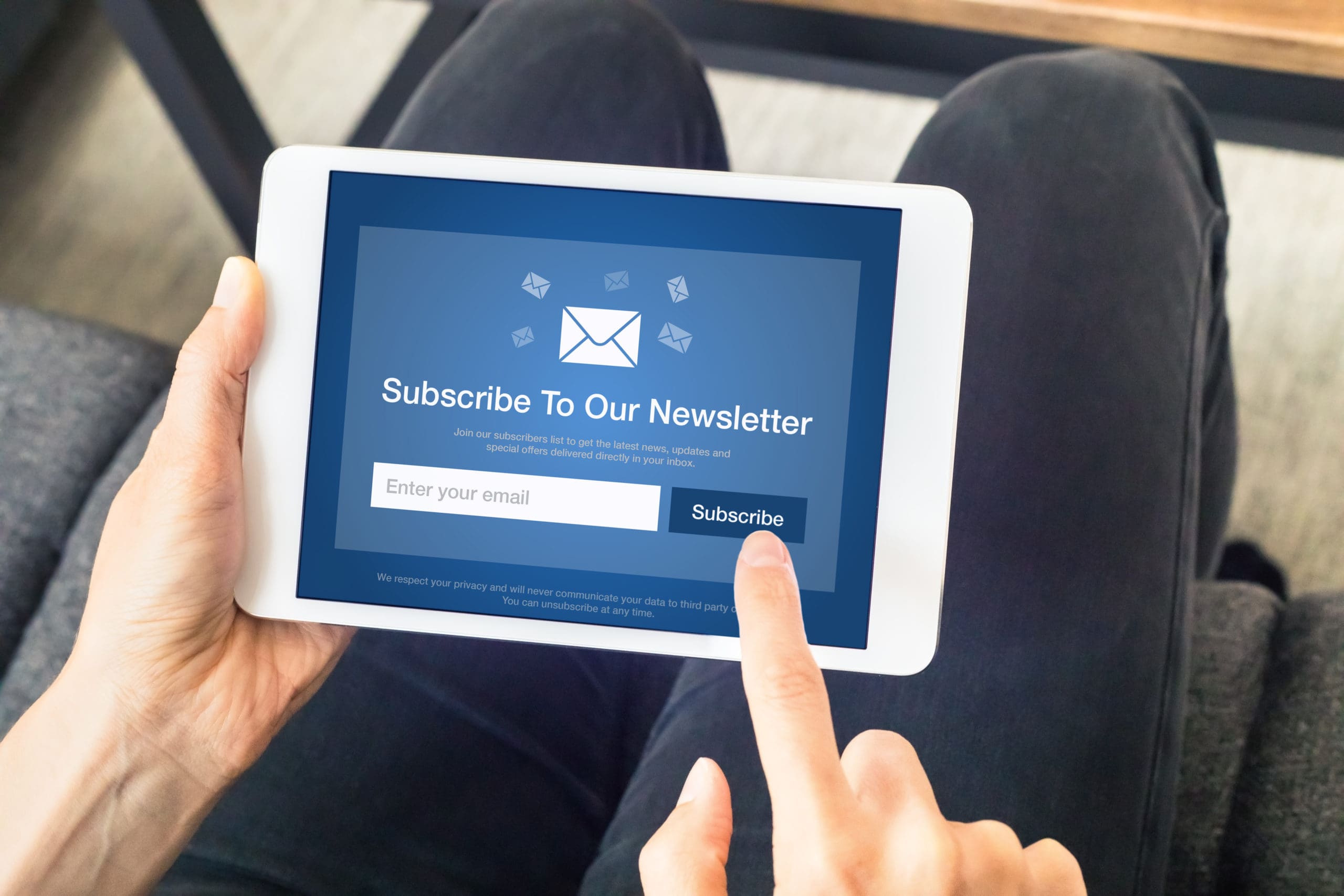 A woman holding a tablet with a subscribe to your newsletter button.