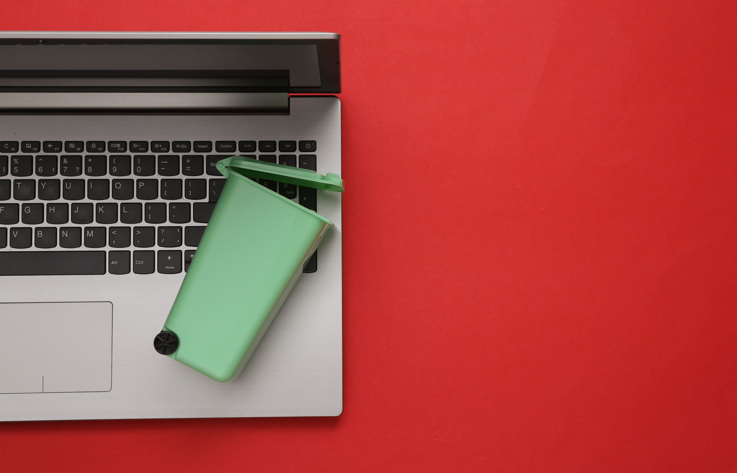 A laptop on a red background with a green cup on it.