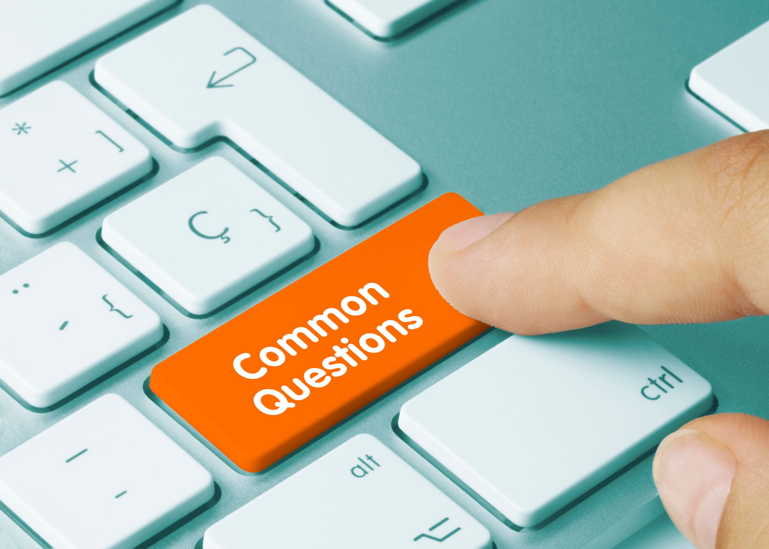 A person pressing a computer key with "common questions" on it, symbolizing a search for faqs or support.